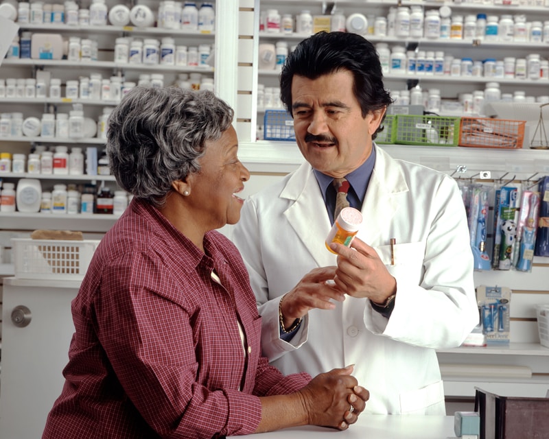 Older adult woman consulting with community pharmacist about her medications. Photo: National Cancer Institute / Rhoda Baer, public domain.