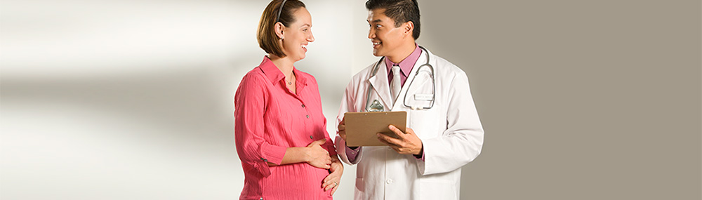 Pregnant woman smiling and talking to her doctor during a prenatal checkup. Photo: NICHD/NIH, public domain.